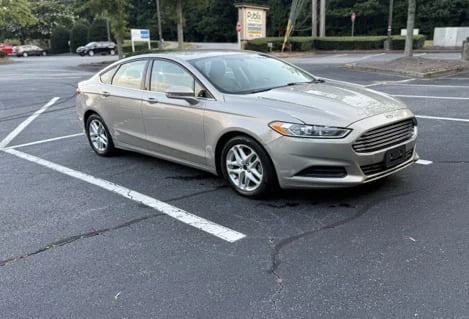 Silver Ford Fusion sedan parked in a parking lot with white line markings